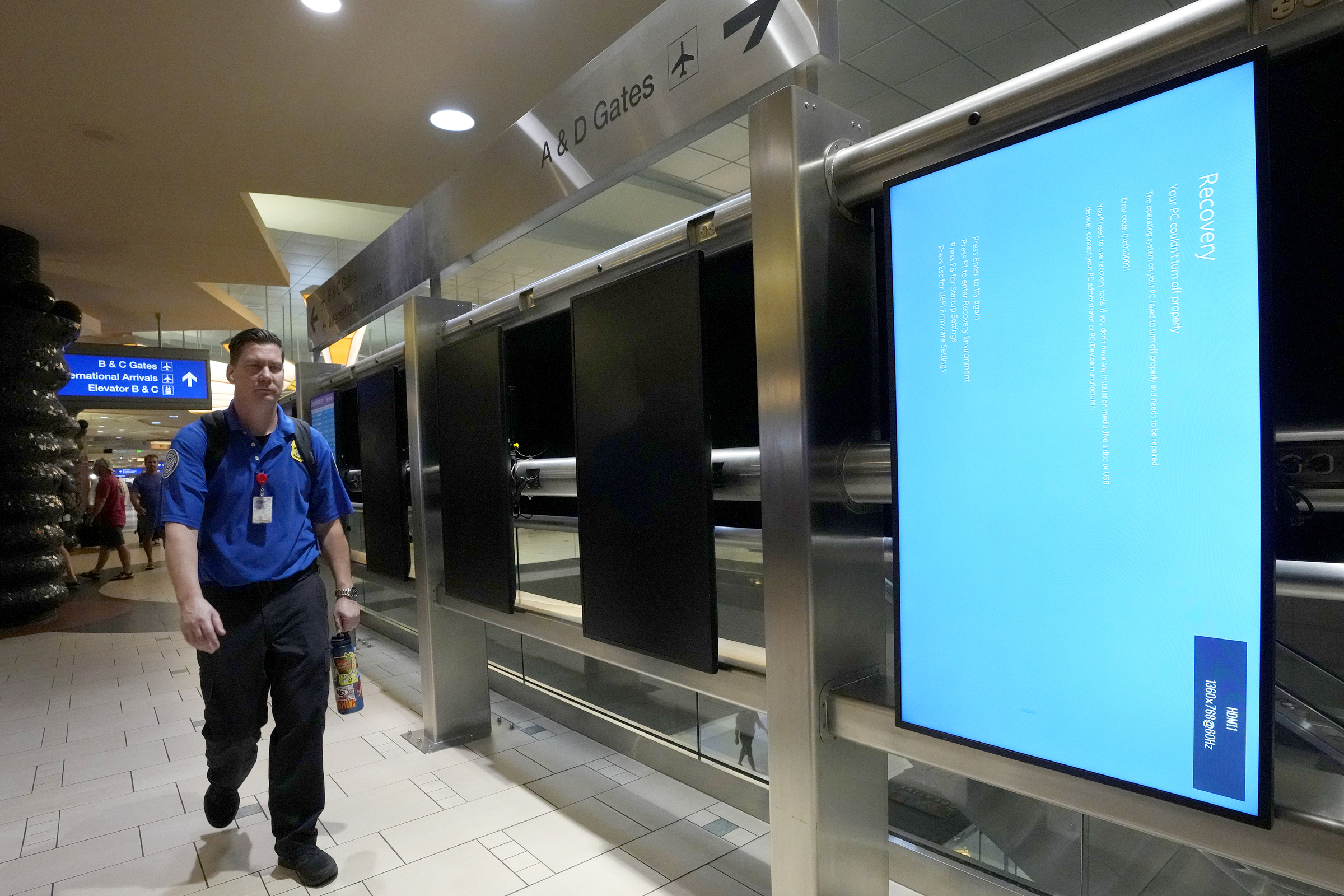 Một người đi ngang qua màn hình quảng cáo bị lỗi tại sân bay quốc tế Phoenix Sky Harbor (Mỹ). Những màn hình khác đã bị tắt. Ảnh: AP