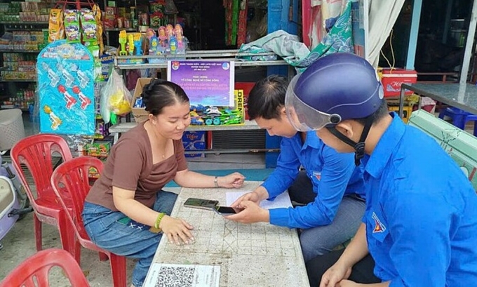 Thành viên Tổ công nghệ số cộng đồng (phải) trong buổi hướng dẫn người dân sử dụng tên miền. Ảnh: Khoa Nguyễn