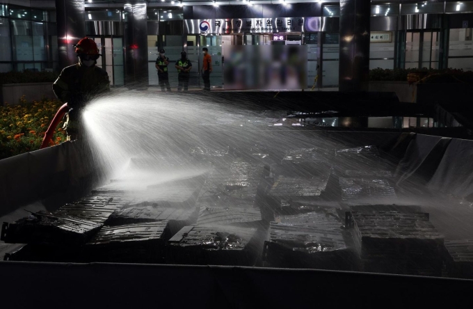 Lính cứu hỏa nhúng pin lithium-ion vào nước để dập tắt đám cháy tại Cơ quan Tài nguyên Thông tin  Quốc gia ở Daejeon. Ảnh: Yonhap