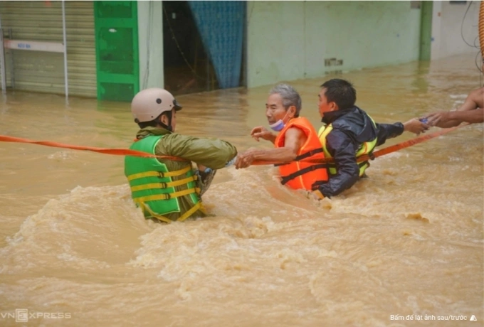 Người dân Nha Trang được lực lượng chức năng hỗ trợ qua dòng nước xiết. Ảnh: Bùi Toàn
