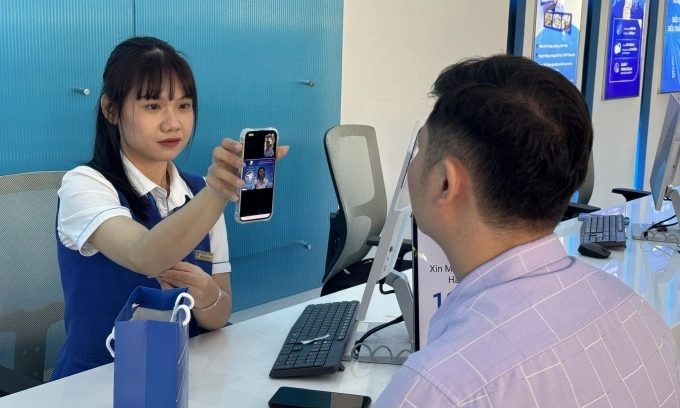 Một khách hàng được nhân viên hỗ trợ làm thủ tục tại điểm giao dịch không giấy tờ, sáng 19/12. Ảnh: Mai Hồng